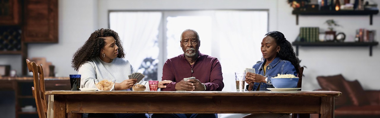 Woman and man sitting at a dinner table with the man placing a hand on the woman's shoulder